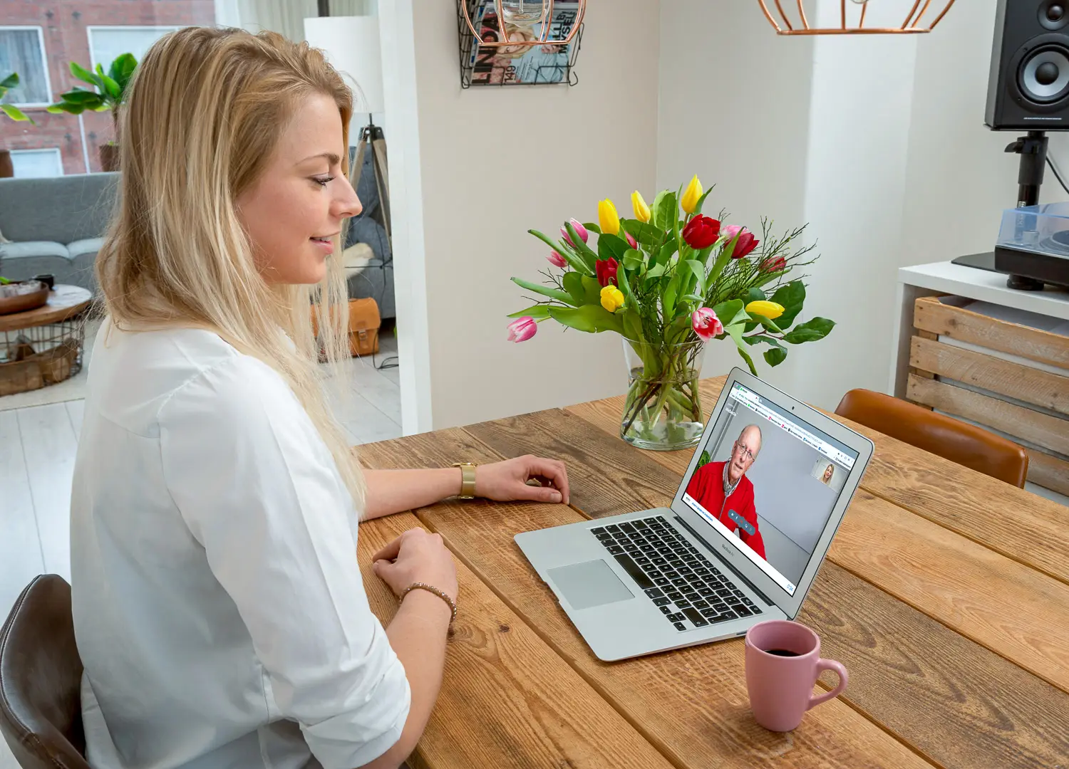 Girl behind computer videocalling at kitchen table