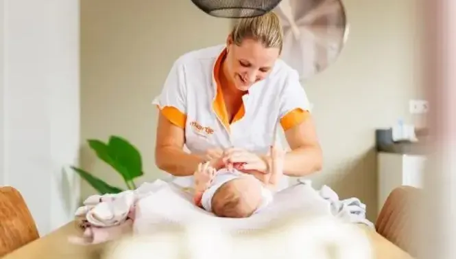 Kraamverzorgster verschoont baby op komode