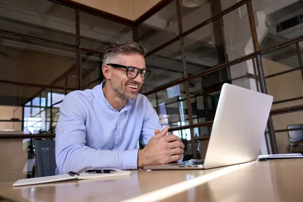 Meneer zit achter laptop te beeldbellen met WeSeeDo in de financiele sector