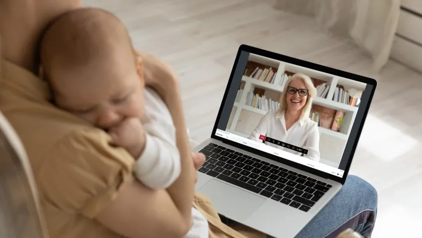 Moeder met net geboren baby aan het videobellen op een Ipad met de kraamverzorgster