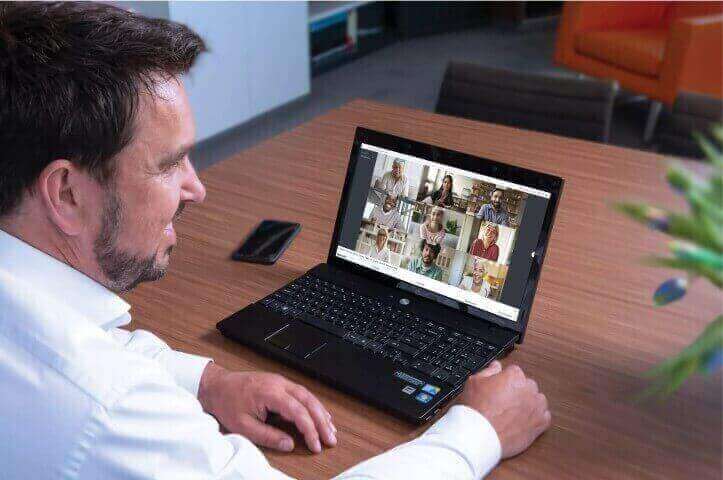 Man in overhemd zit achter zijn laptop in online groepsgesprek