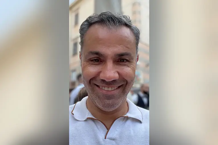 Selfie van huisarts Ali Akyuz met en overhemd die de camera in kijkt en lacht.