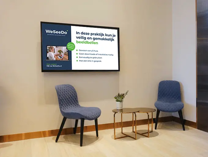 Moderne wachtkamer met TV. TV toont 'WeSeeDo' advertentie over beeldbellen; twee blauwgrijze stoelen en tafel met vaas.